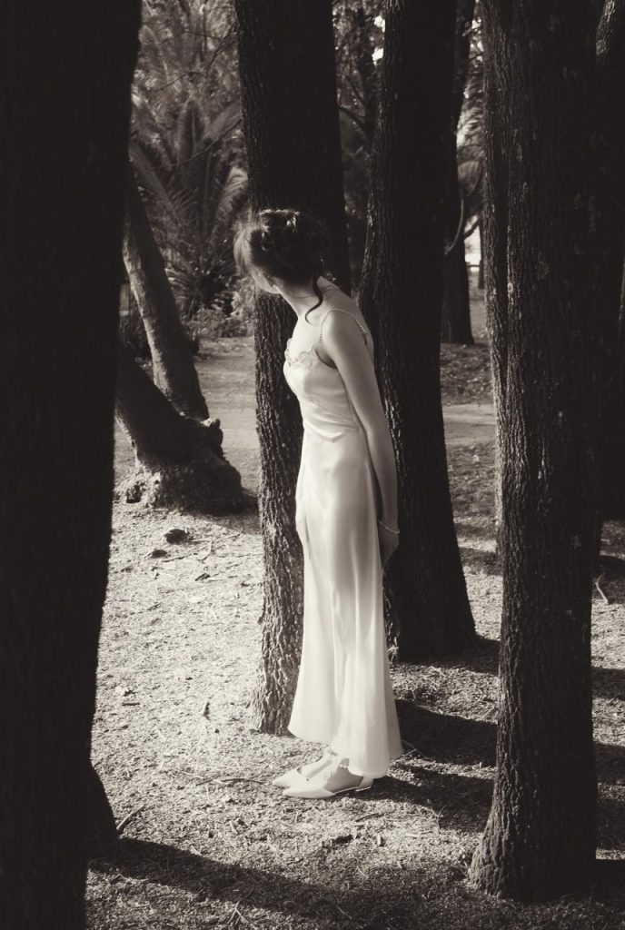 Page midst a forest, poking her head behind a tree. 